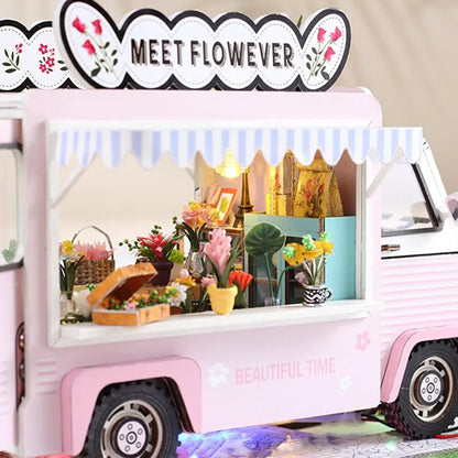 a pink food truck with flowers on the top of it